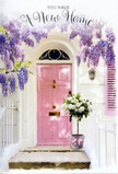The photograph presents a serene doorway scene that feels perfectly suited to a leafy side street near Lea Bridge Station, where homes often mix urban character with unexpected softness. A light pink door stands at the centre, its pastel shade tender and inviting against walls brushed in clean white. The surface of the door looks hand-painted, with a matte, slightly textured finish that catches the subdued daylight. Above and partially beside it, cascades of wisteria tumble down in loose lavender garlands, their clustered blooms forming a graceful arch that frames the entrance in natural colour and shade. The petals vary from deeper lilac tones in the shadows to almost silvery lavender where the light touches them, giving a sense of depth and abundance. On the doorstep, a simple grey bucket, the kind an experienced florist might use in a studio off Lea Bridge Road, holds a generous bouquet of white and cream roses. Each flower is fully open and lush, soft petals overlapping like folded fabric, with tips that catch the light and glow faintly against the surrounding greenery. Sprigs of fresh green foliage peek between the roses, offering gentle contrast and a feeling of freshness, as though the stems were just conditioned in cool water. A satin ribbon in blush pink is tied around the base of the bucket, its sheen echoing the colour of the door and adding a delicate, celebratory flourish. The overall atmosphere is one of quiet joy and anticipation, evoking the moment someone arrives at their new home near Millfields Park and finds a housewarming bouquet waiting at the threshold-flowers that whisper welcome, steady the nerves, and mark the start of life in Lea Bridge with softness and grace.